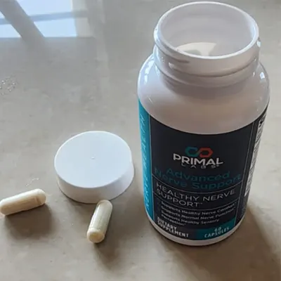 A bottle of capsules with a white label that says Primal Avanc Healthy Nerve Support in black lettering, sitting on a table.